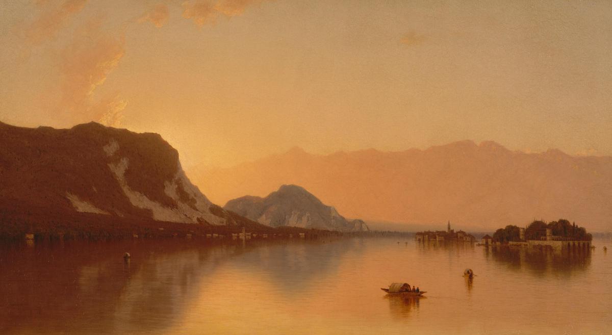 In ein warmes orange getaucht, erstreckt sich eine Berglandschaft bist dicht an einen großen See. Einige Segelschiffe sind auf dem Wasser, eine kleine Insel auf der eine Burg zu erkennen ist.